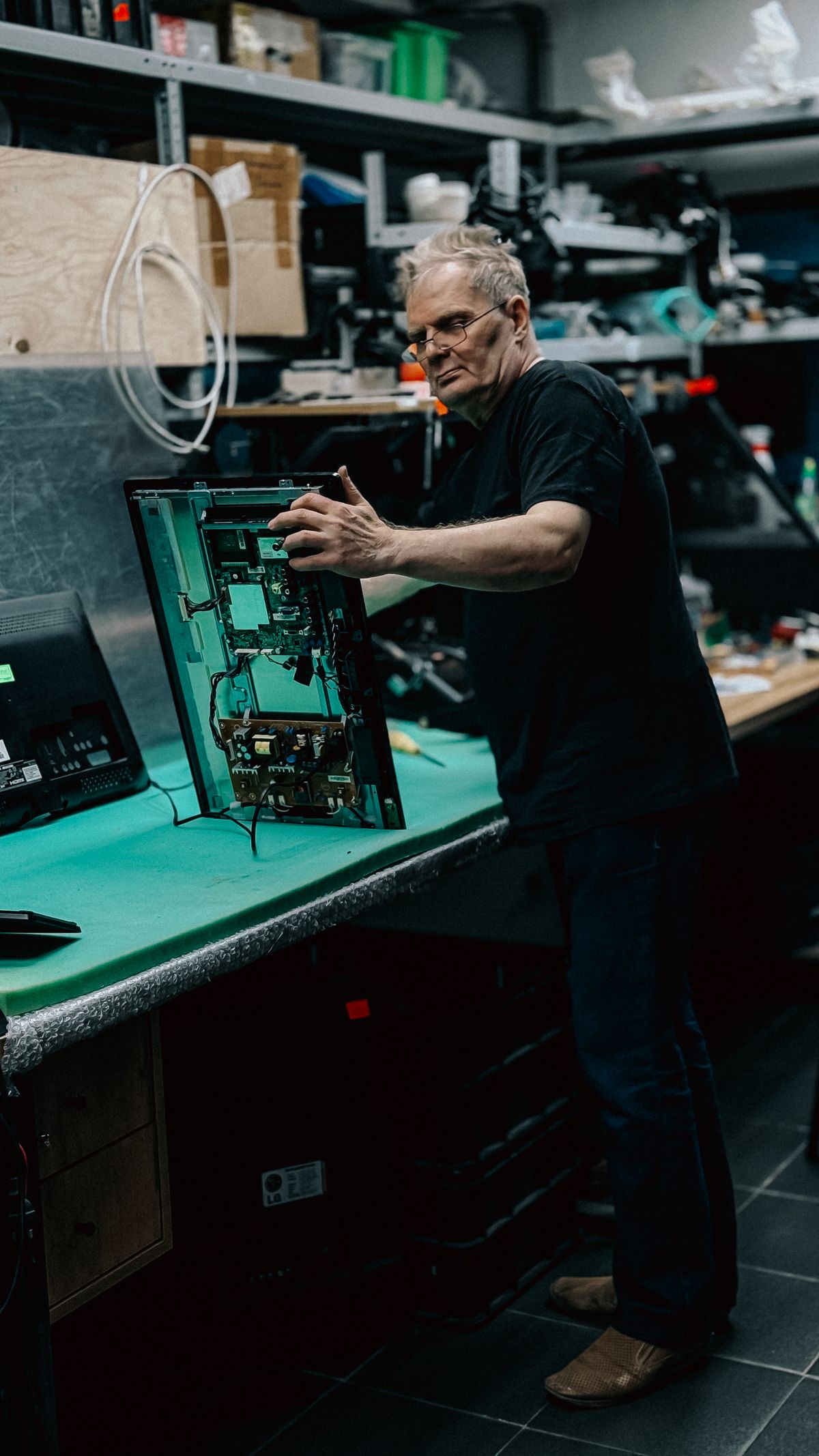 A monochrome workshop technician inspecting electronic equipment.