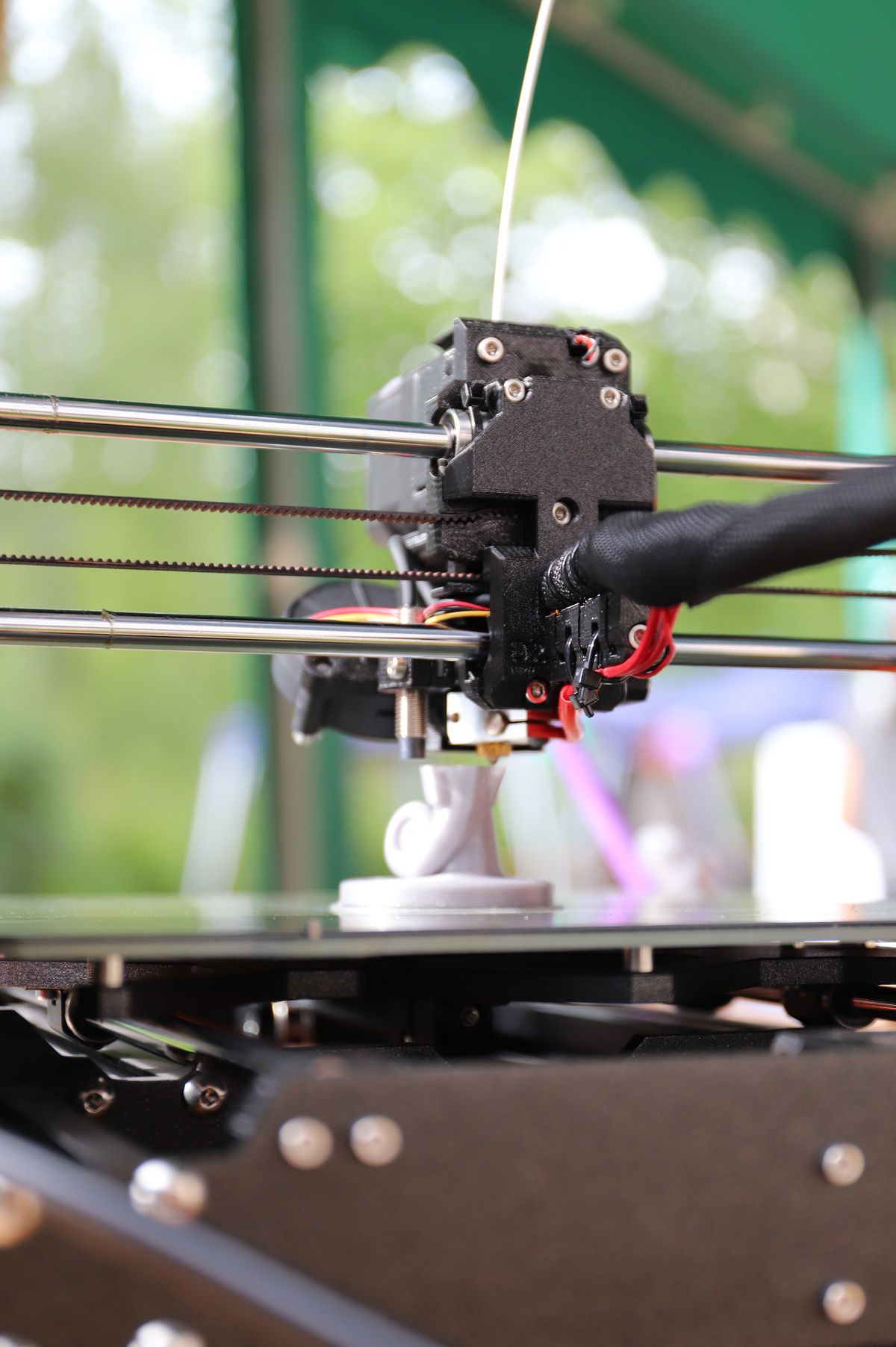 Monochrome photograph: A 3D printer producing a physical component.