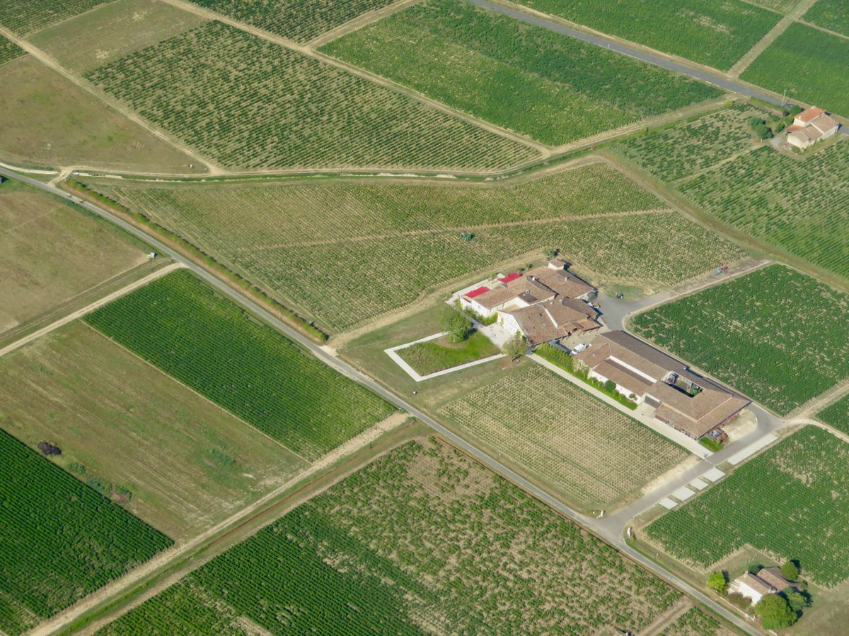 Monochrome photograph: Agricultural fields and farm buildings seen from above.